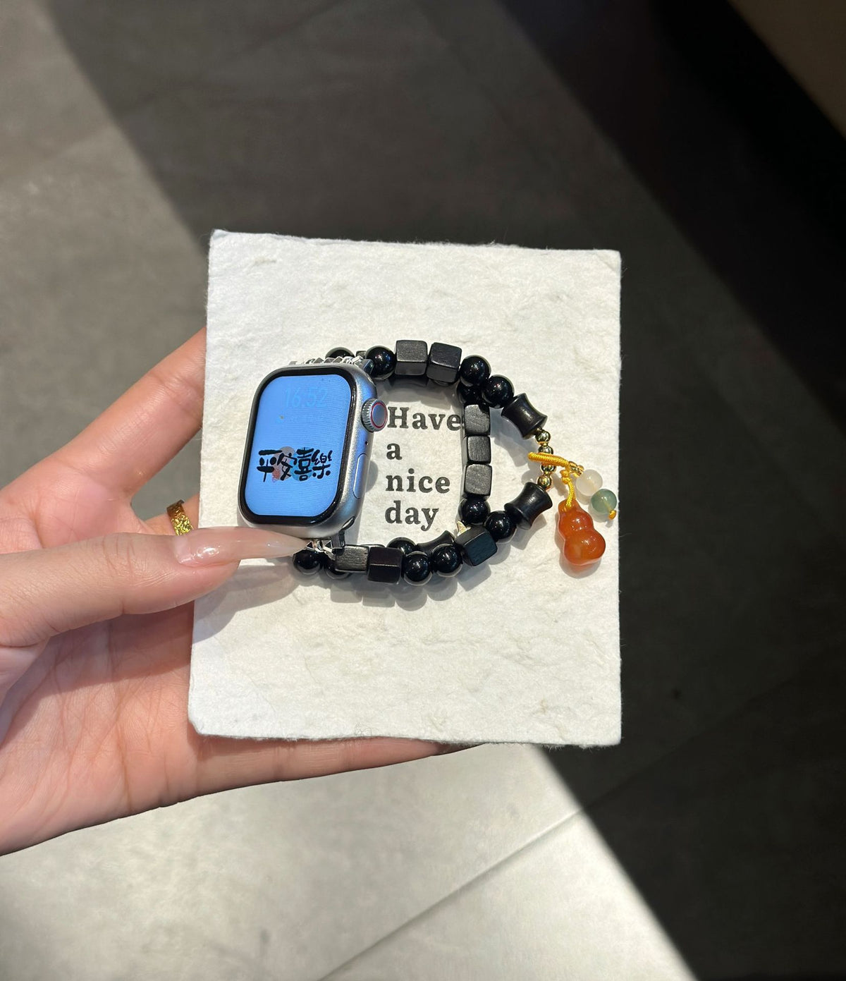 Black beaded amber charm Apple Watch bracelet band displayed on textured card