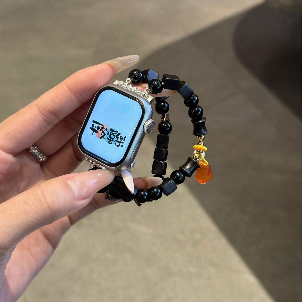 Black beaded amber charm Apple Watch bracelet band held in hand