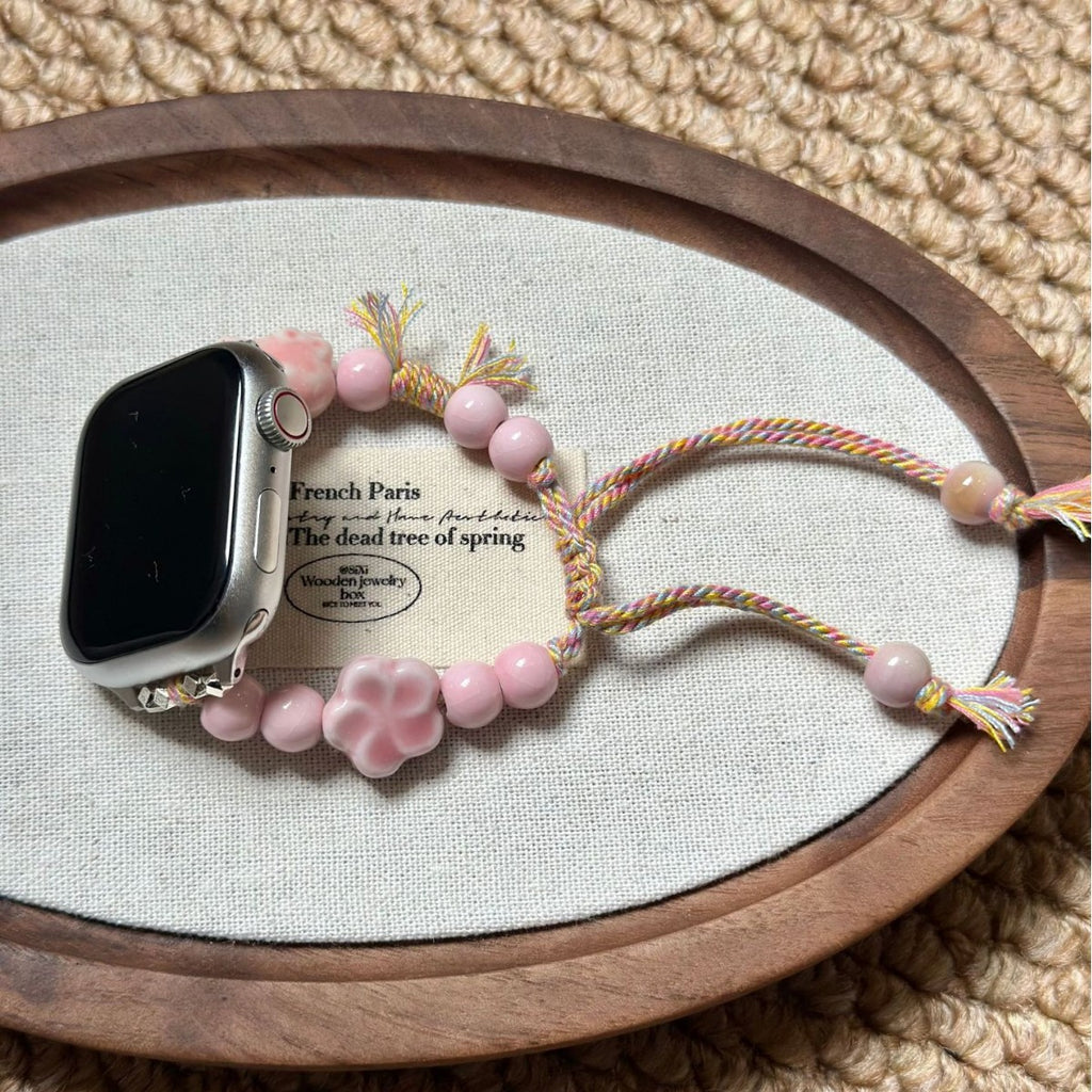 Pink flower beaded Apple Watch band displayed on fabric tray
