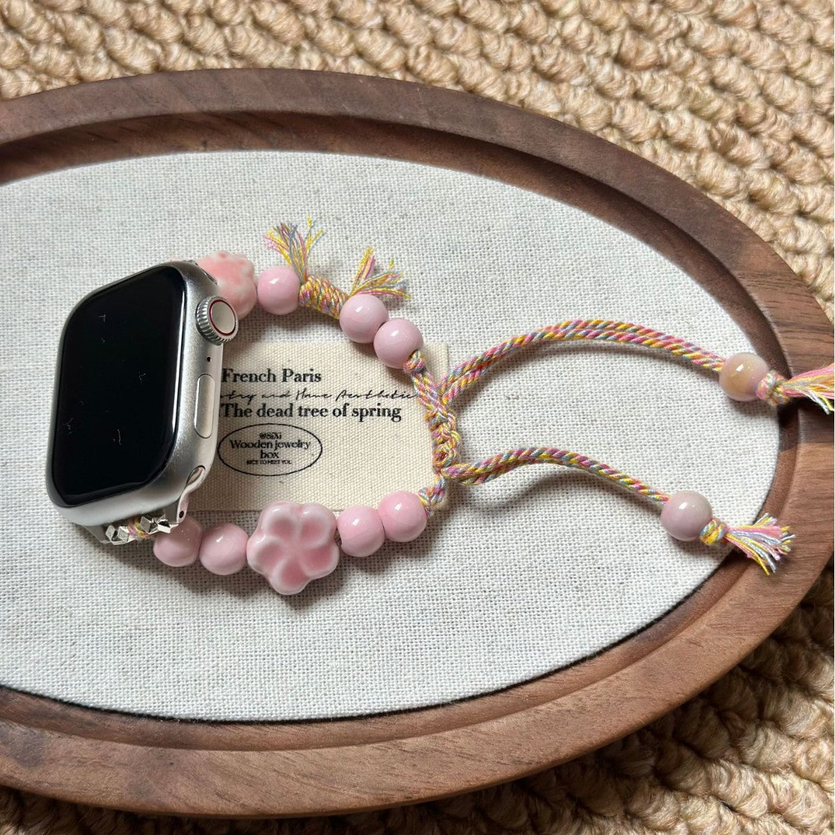 Pink flower beaded Apple Watch band displayed on fabric tray