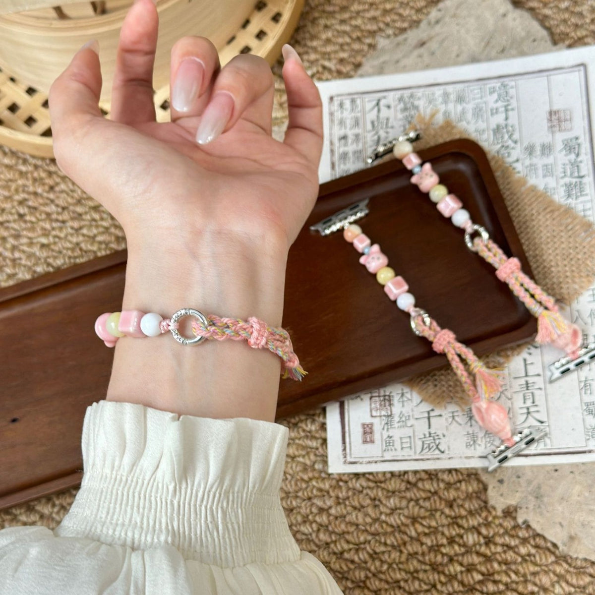 Pink braided beaded Apple Watch band worn on wrist