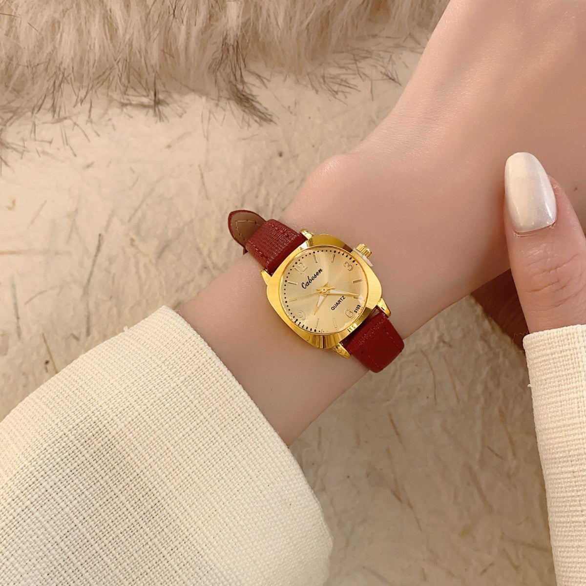 CABOSEN vintage small women's watch with gold-tone case, champagne dial and burgundy leather-style strap on wrist