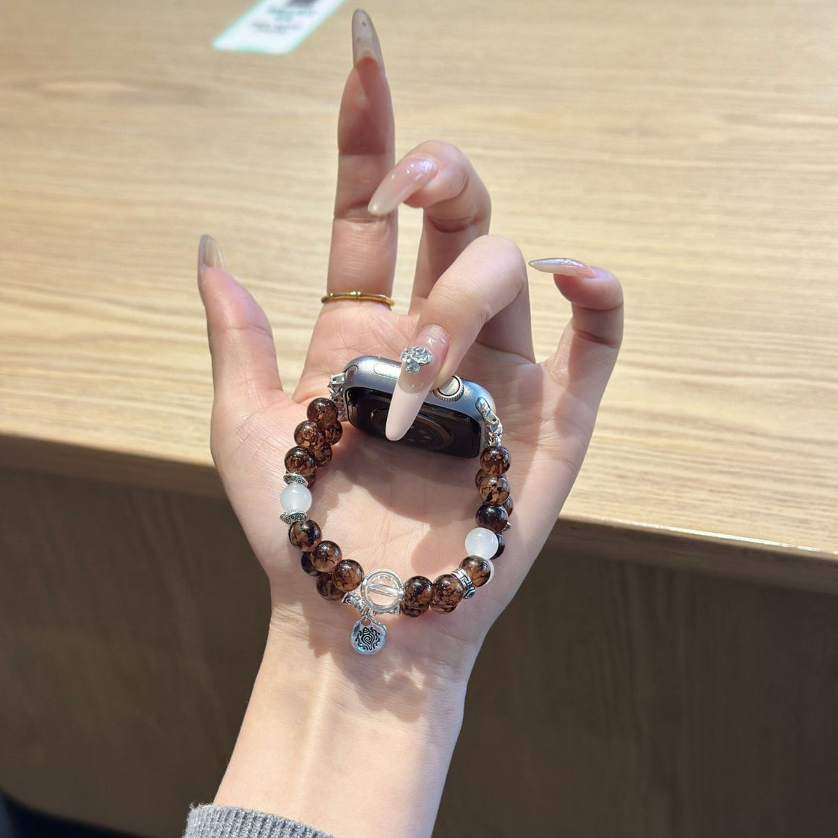 Cocoa brown and clear beaded Apple Watch bracelet band held in hand