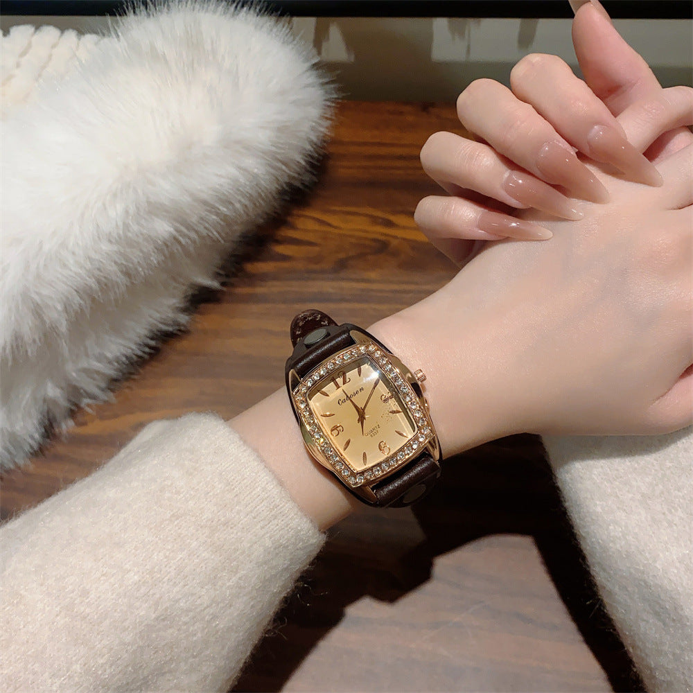 Vintage crystal tonneau women's watch with black leather strap and champagne dial on wrist