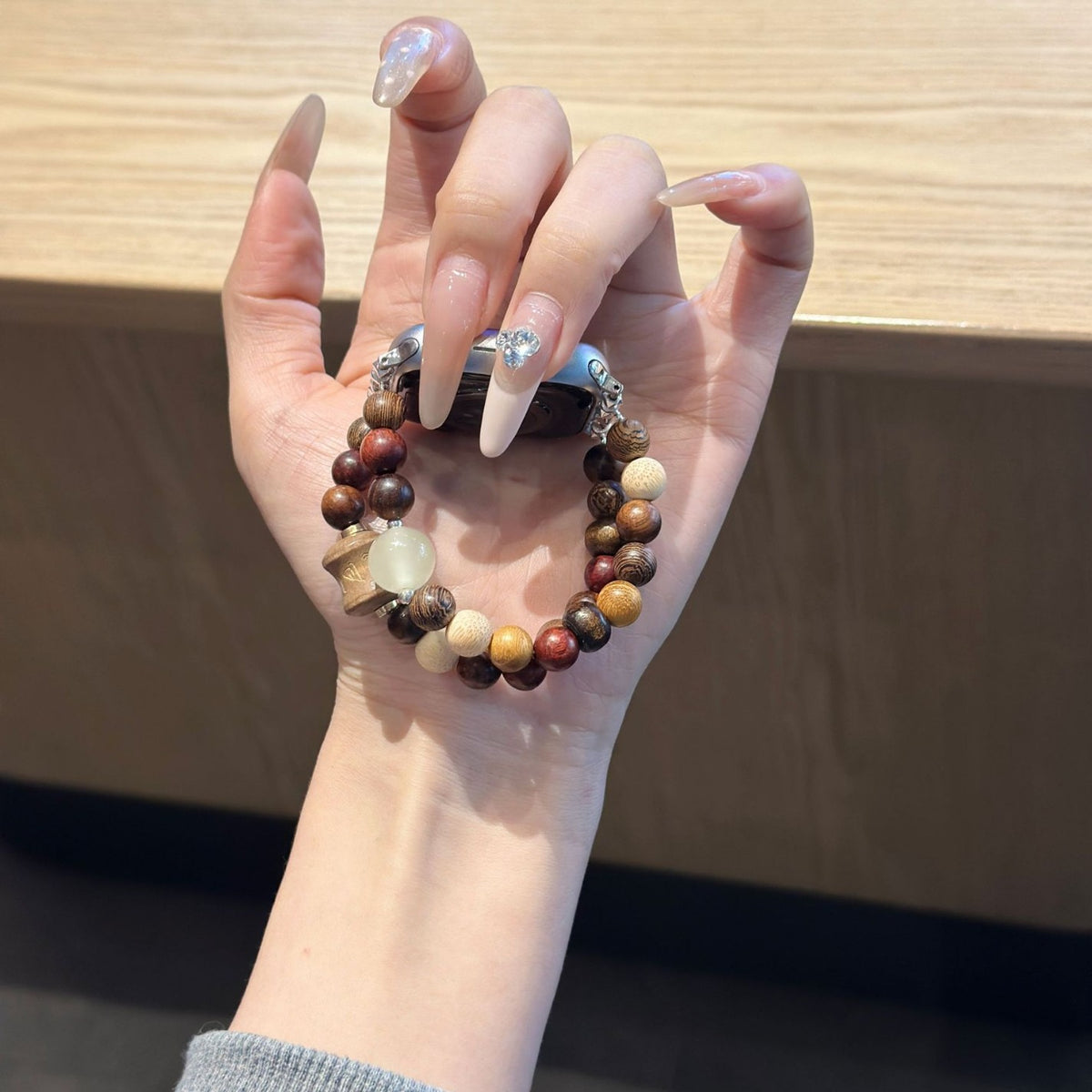 Earth-tone mixed bead Apple Watch bracelet band held in hand