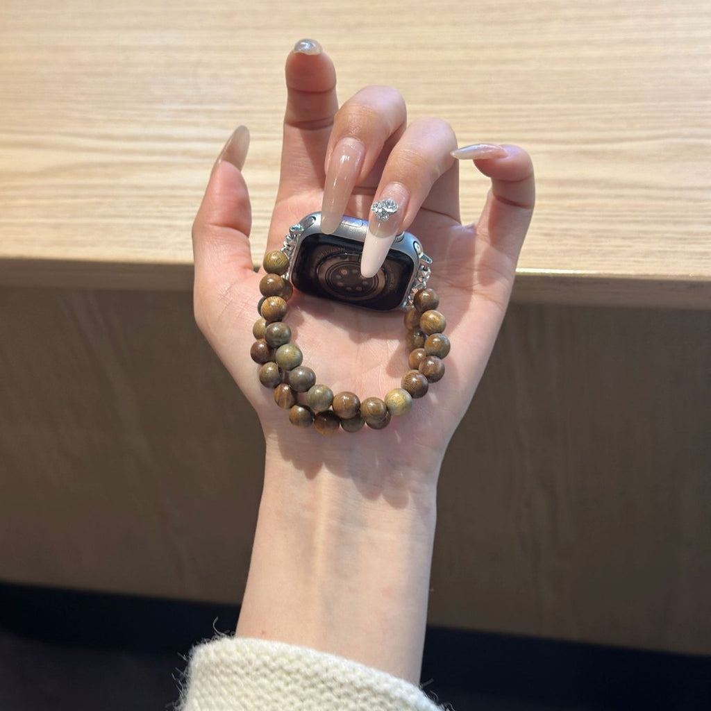 Brown double-strand beaded Apple Watch bracelet band held in hand