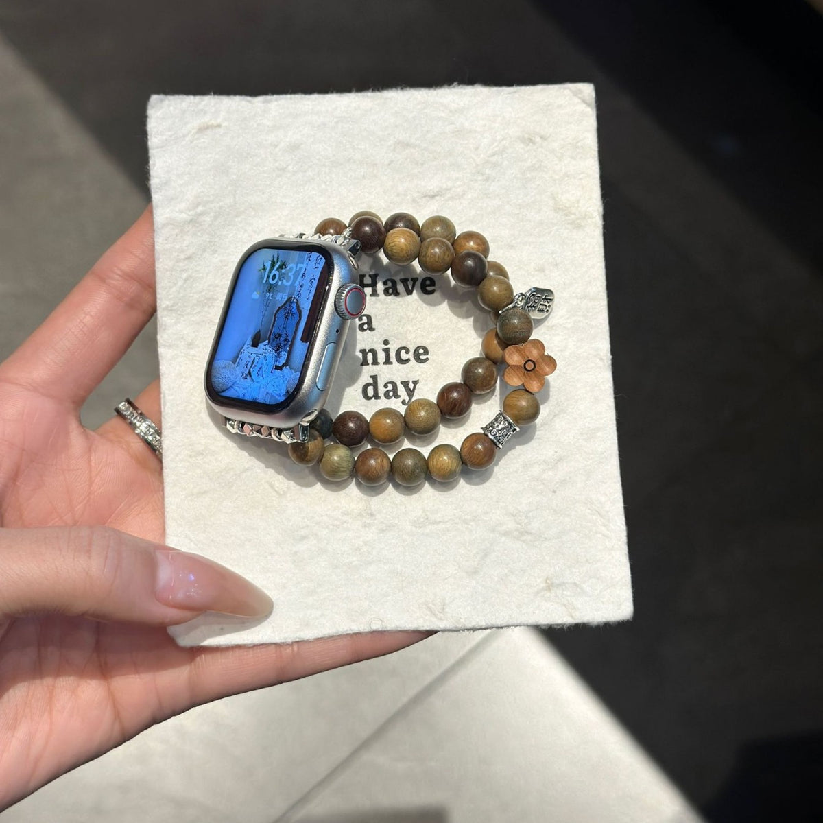 Double-strand wood-bead Apple Watch band displayed on textured card