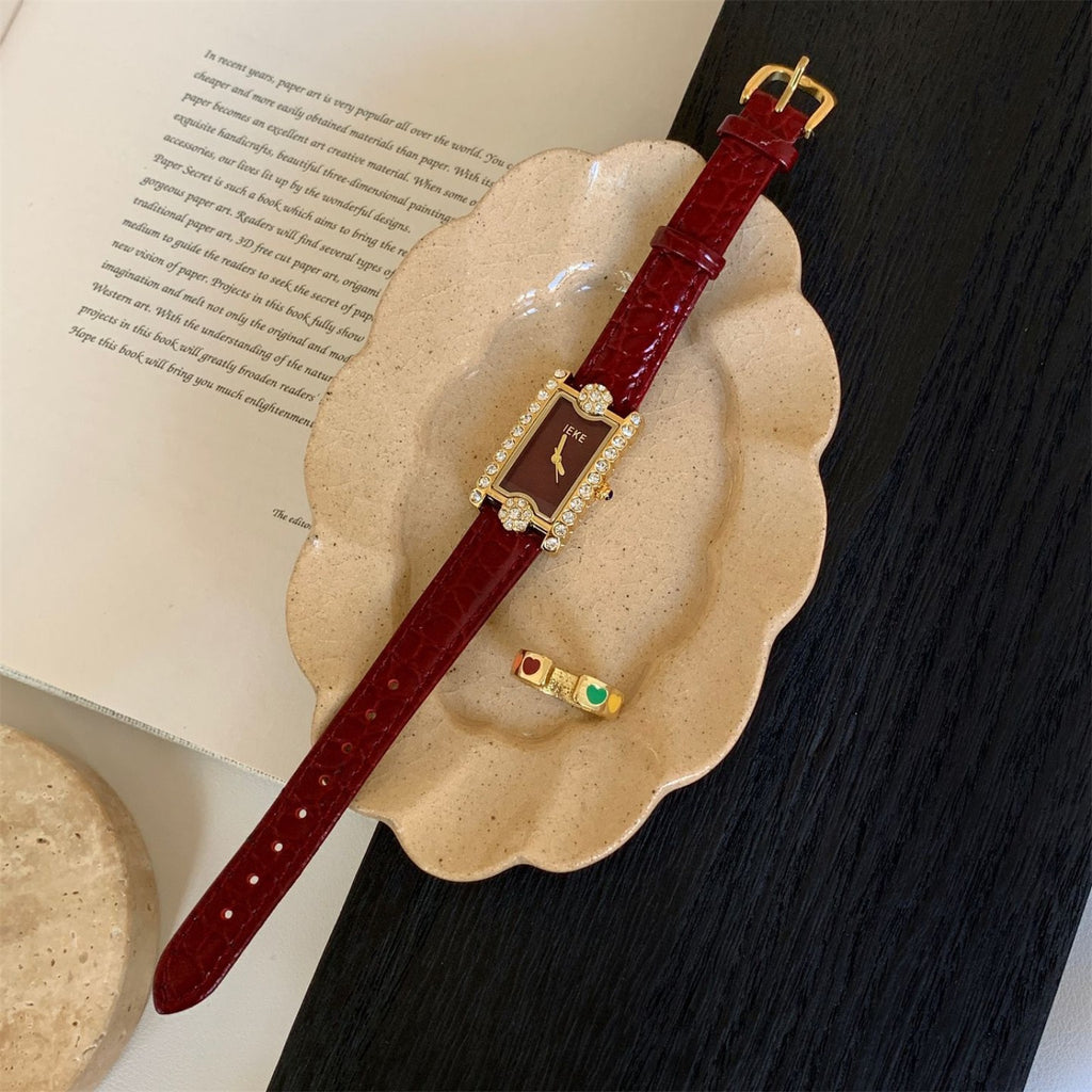 IEKE burgundy rectangular crystal watch with gold-tone case in editorial flat lay
