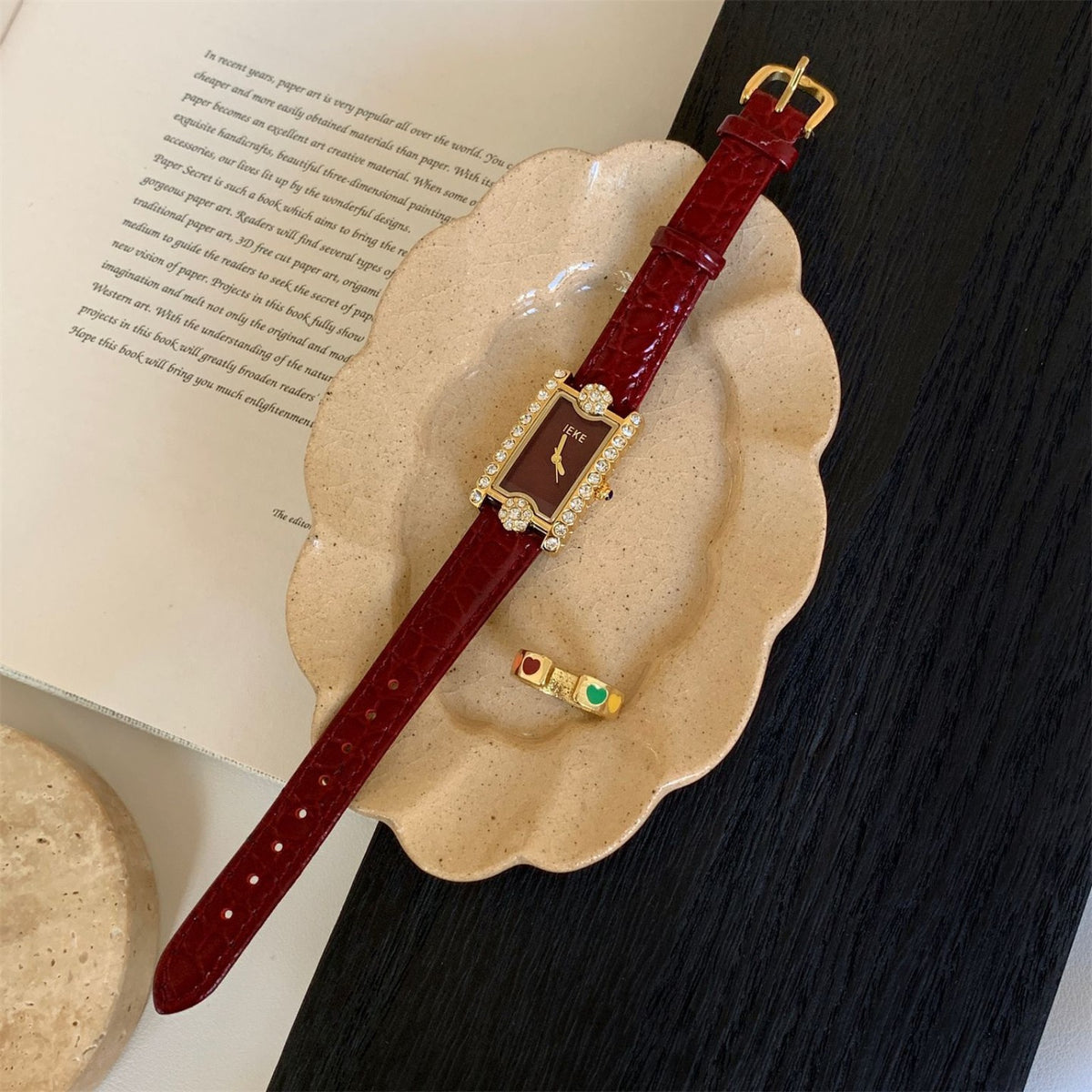 IEKE burgundy rectangular crystal watch with gold-tone case in editorial flat lay