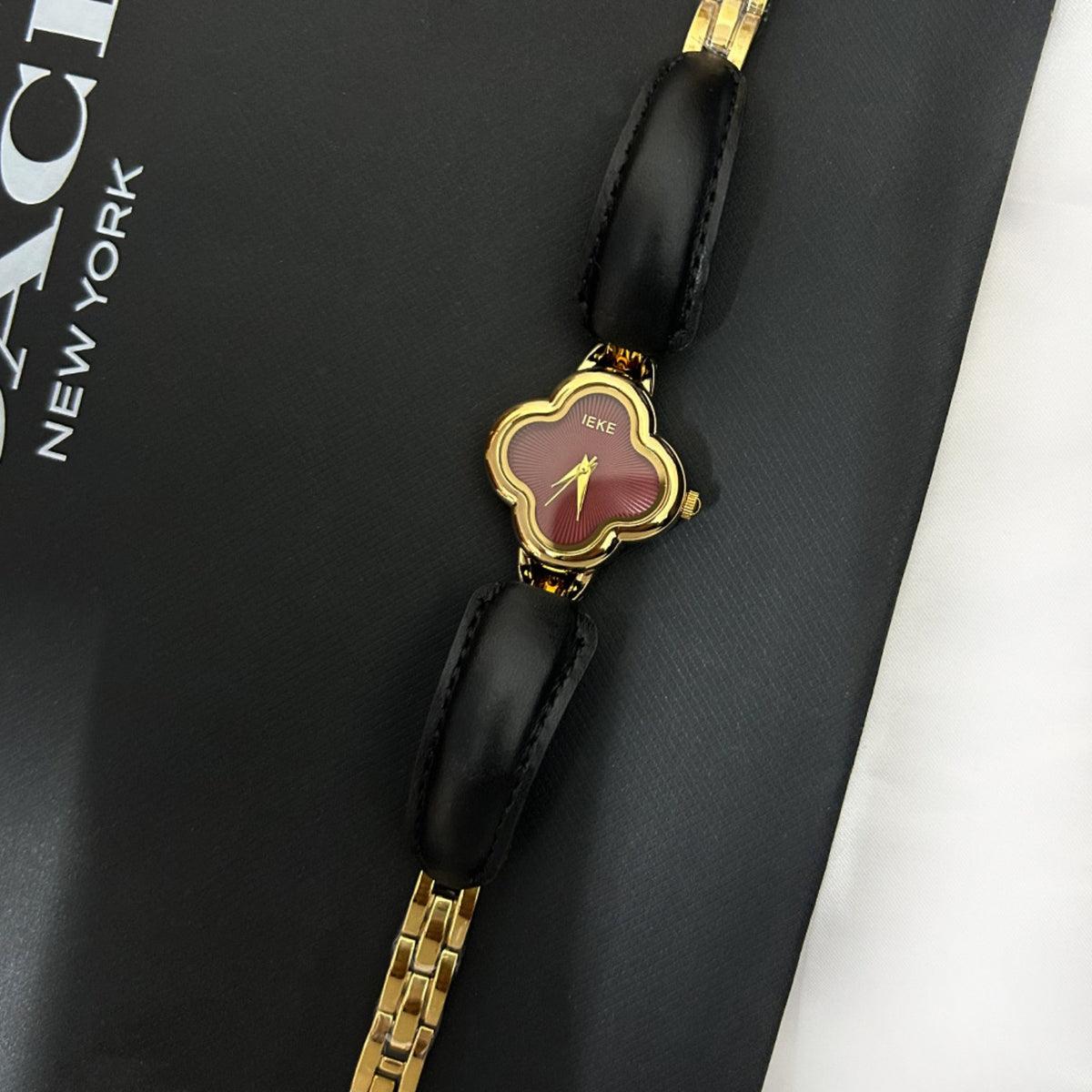 IEKE clover-shaped women's watch in gold with burgundy dial and black leather accents