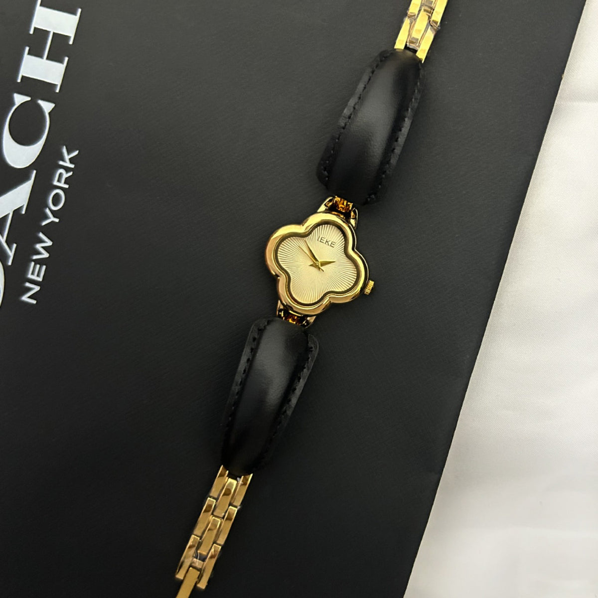 IEKE clover-shaped women's watch in gold with champagne dial and black leather accents