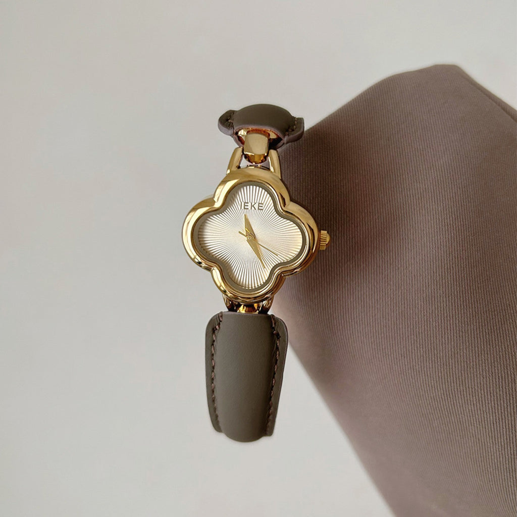 Detail view of IEKE gold clover-shaped women's watch with ivory dial and taupe leather accents