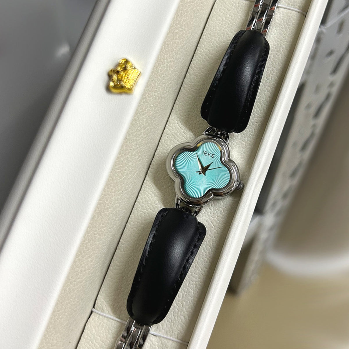 IEKE clover-shaped women's watch in silver with aqua dial and black leather accents