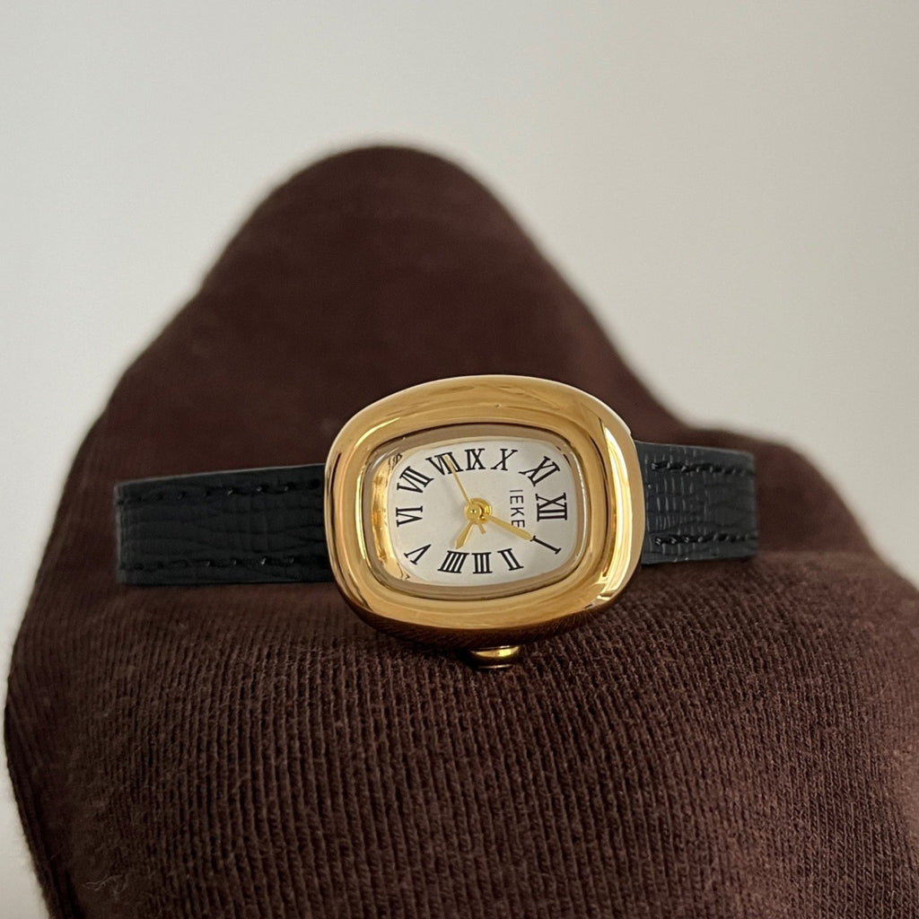 IEKE petite women's Roman numeral quartz watch with gold-tone oval case, white dial and black leather-style strap