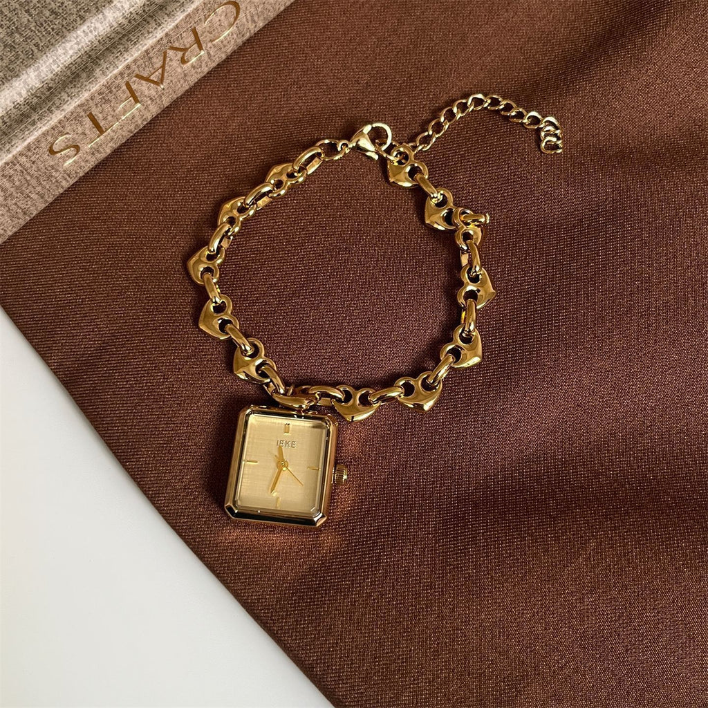 Detail view of IEKE gold-tone heart-link bracelet watch with champagne dial