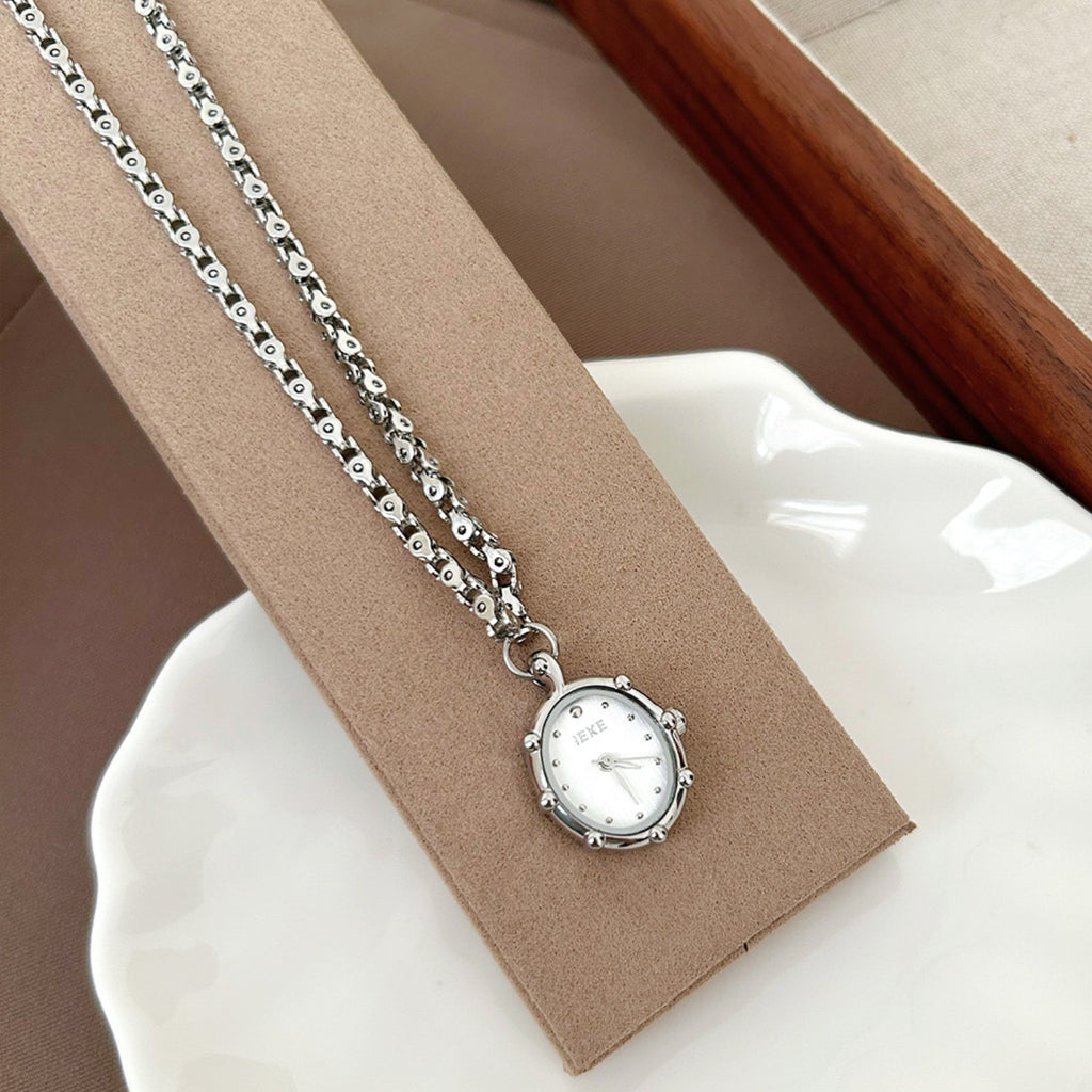 IEKE silver pendant necklace watch displayed on beige stand
