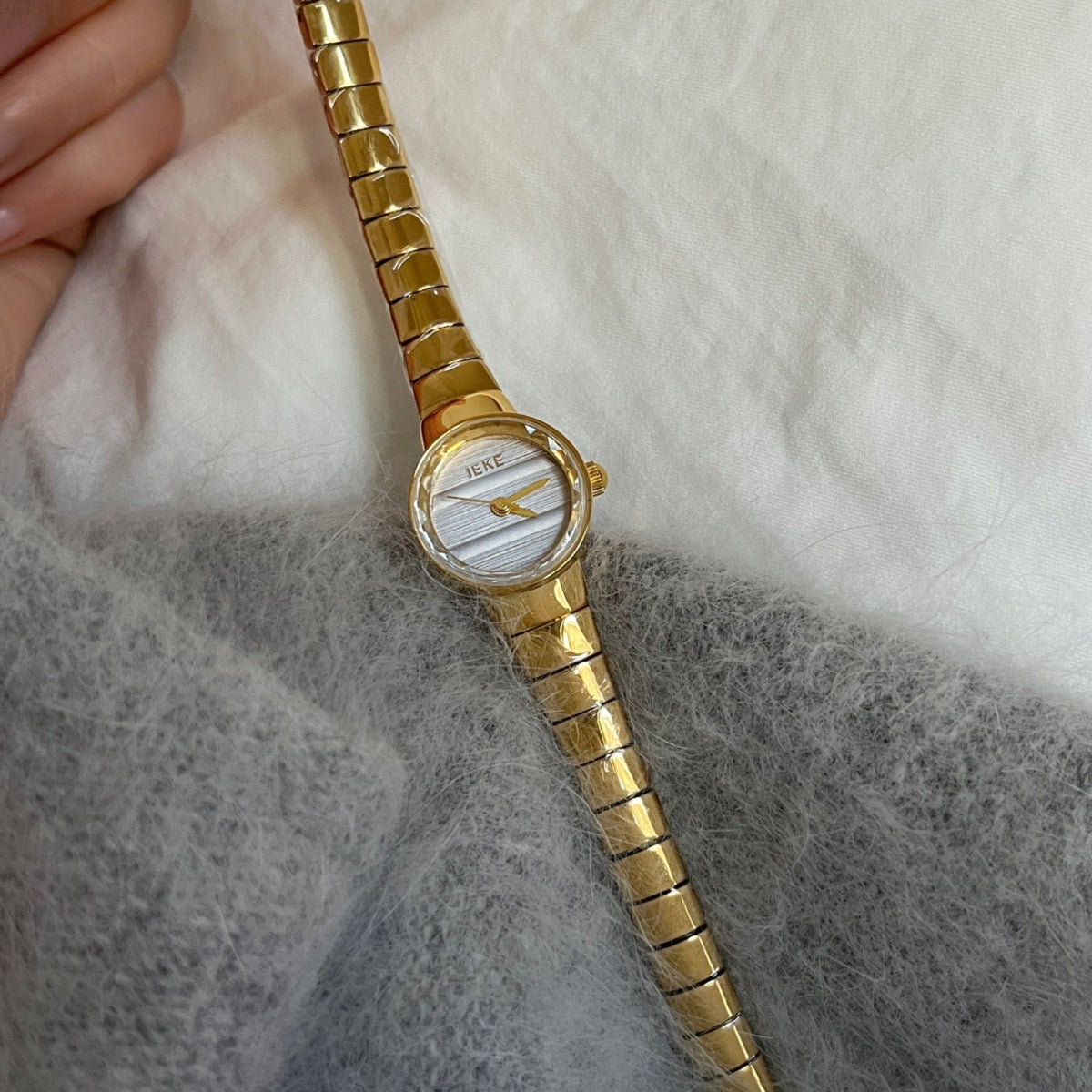 IEKE petite women's gold-tone watch with light silver-white dial styled on soft knit fabric