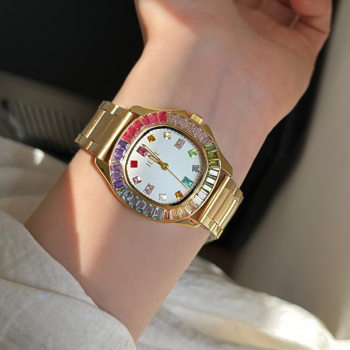 IEKE women's rainbow crystal bracelet watch with gold-tone bracelet and white dial worn on wrist