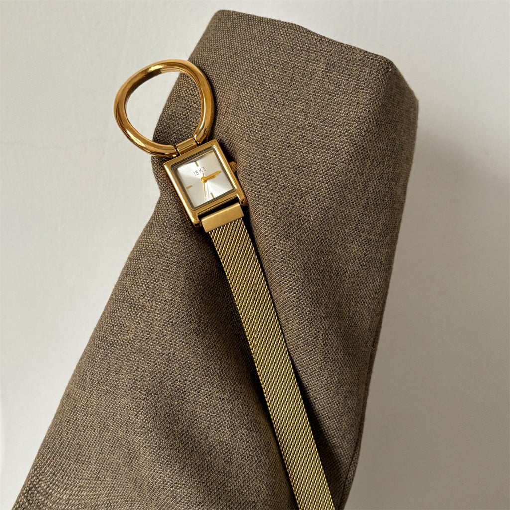 IEKE gold square watch with magnetic mesh strap styled on a neutral cushion