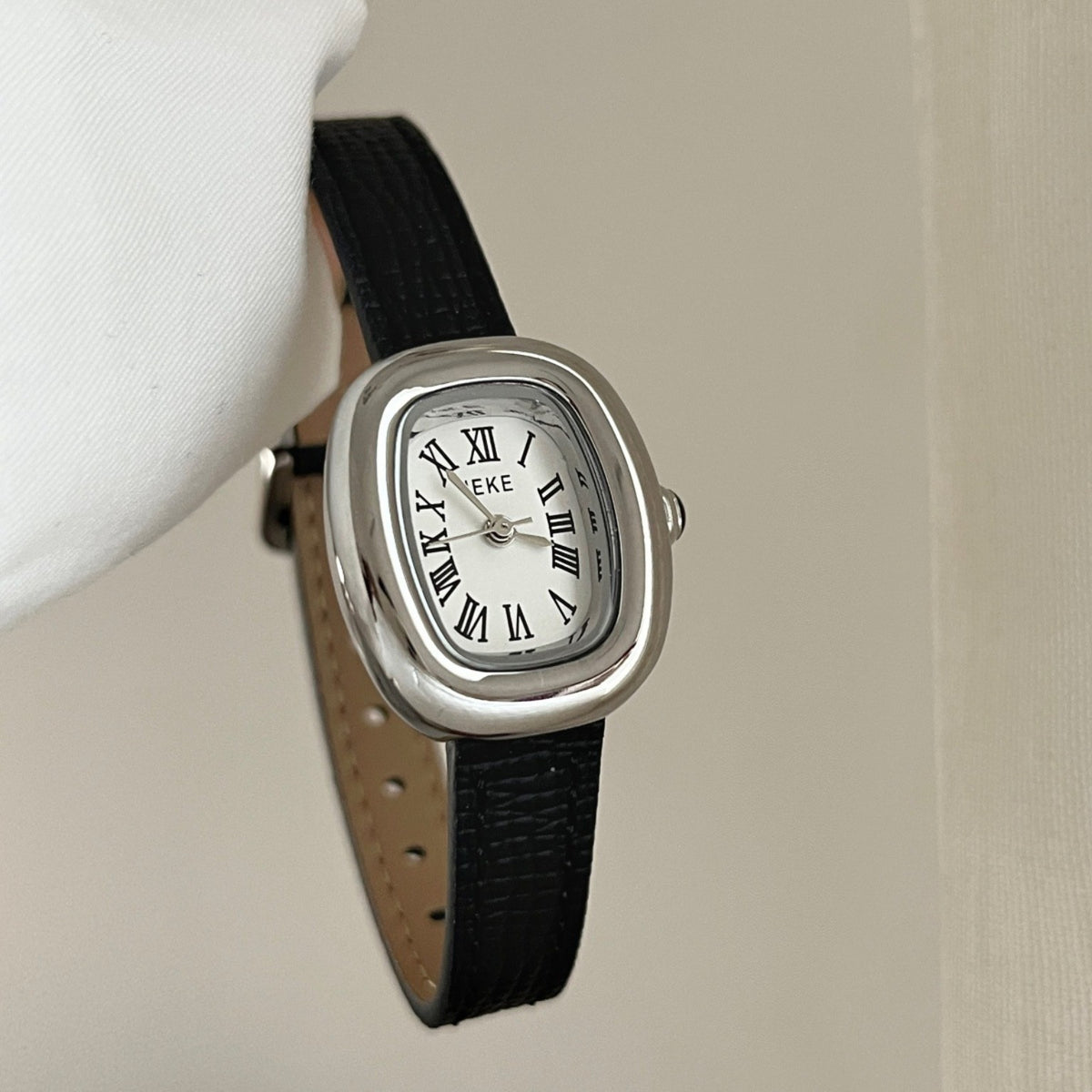 IEKE petite women's Roman numeral quartz watch with silver-tone oval case, white dial and black leather-style strap