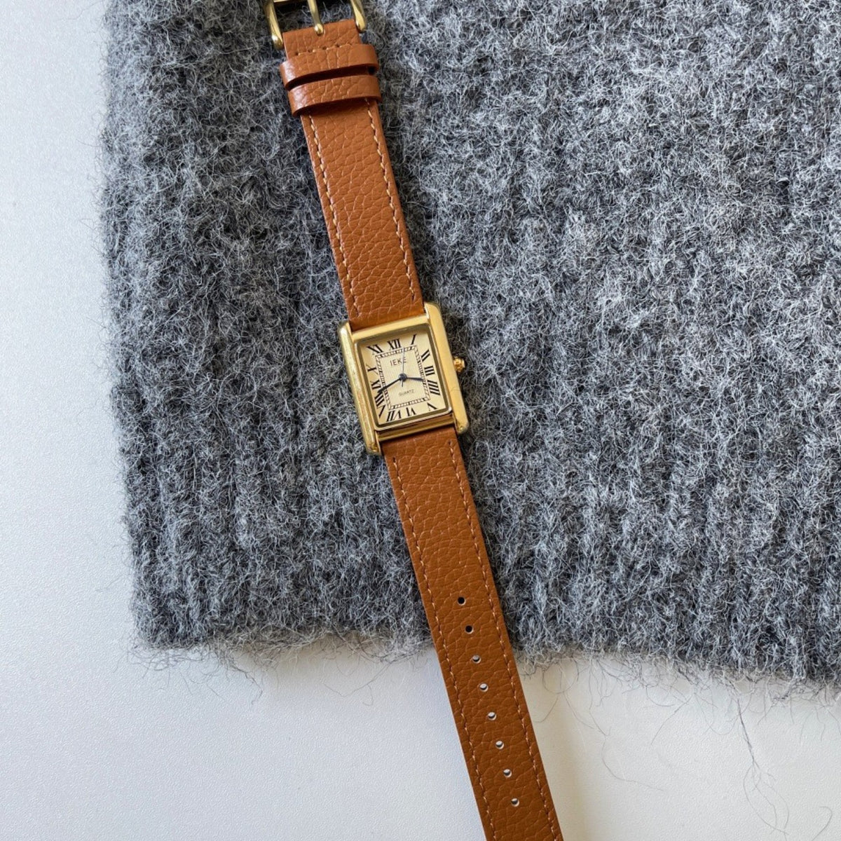 IEKE rectangular Roman numeral women's watch with brown strap styled on grey knitwear