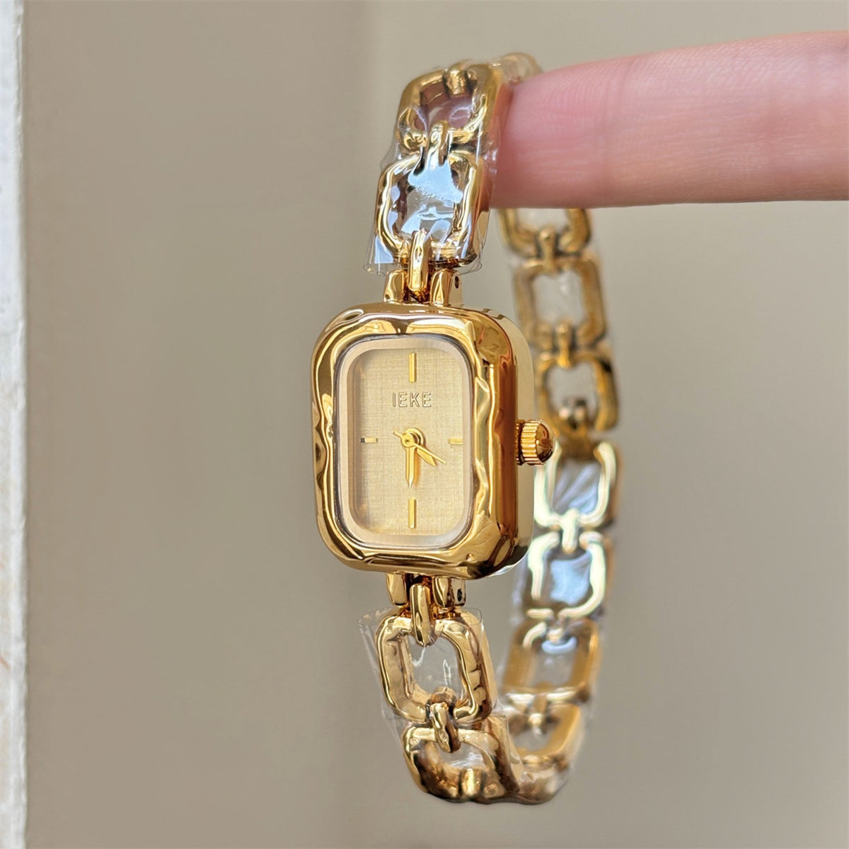 Close-up of IEKE women's sculpted link square bracelet watch in gold with ivory dial
