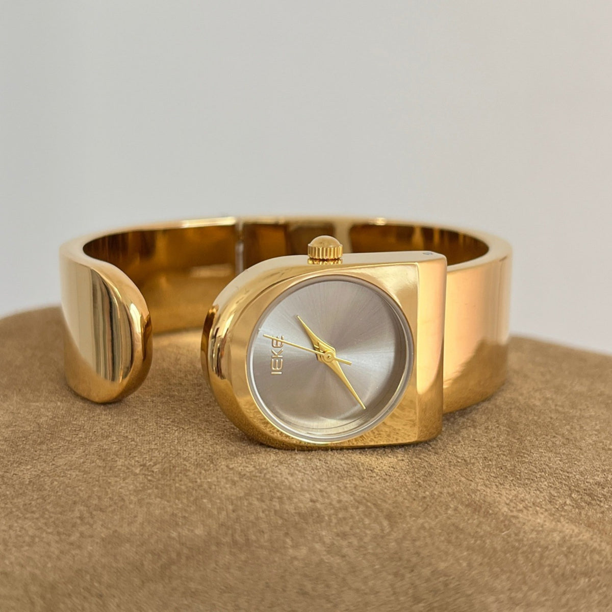 IEKE sculptural cuff bracelet watch in polished gold with silver sunray dial