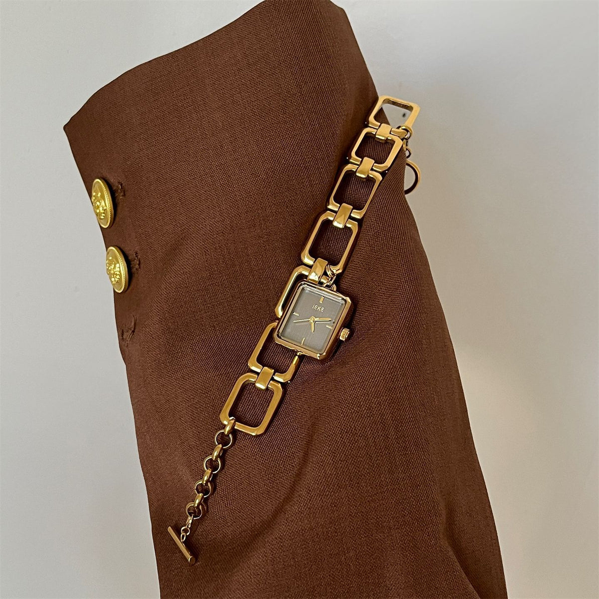 IEKE vintage charm bracelet watch with white dial styled against brown fabric