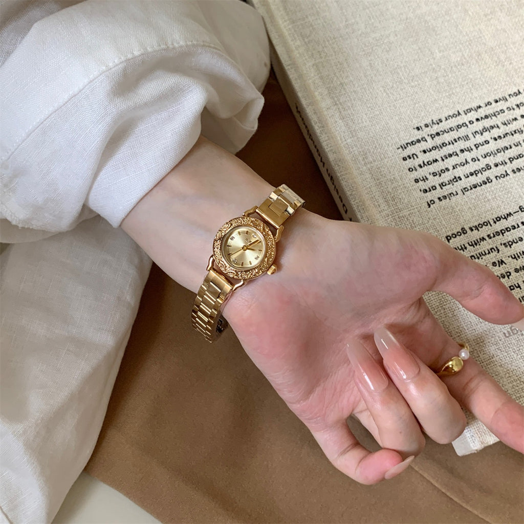 IEKE petite gold-tone vintage women's watch worn on wrist with decorative embossed bezel