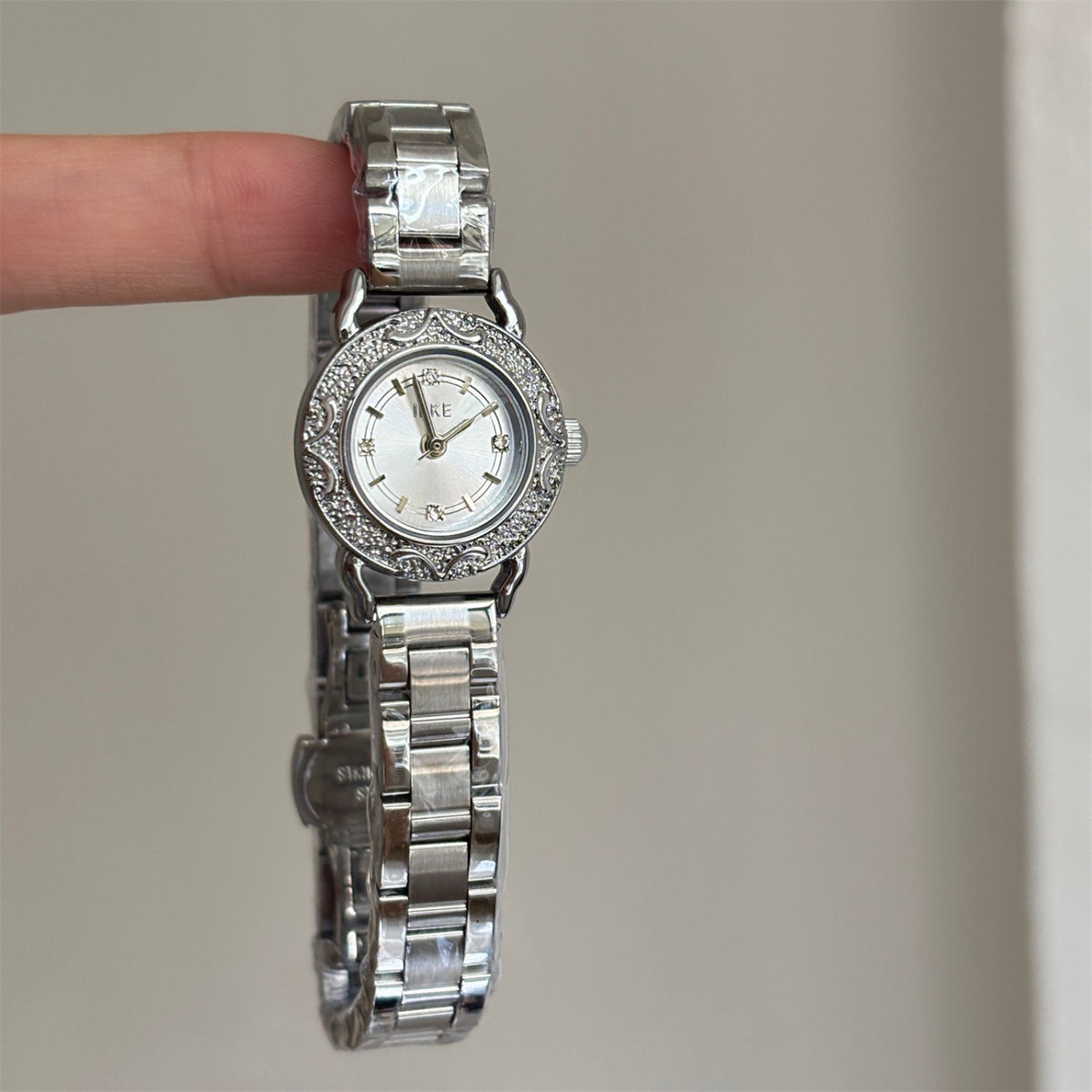 Close-up of IEKE silver-tone petite women's watch with crystal-style markers and ornate vintage bezel