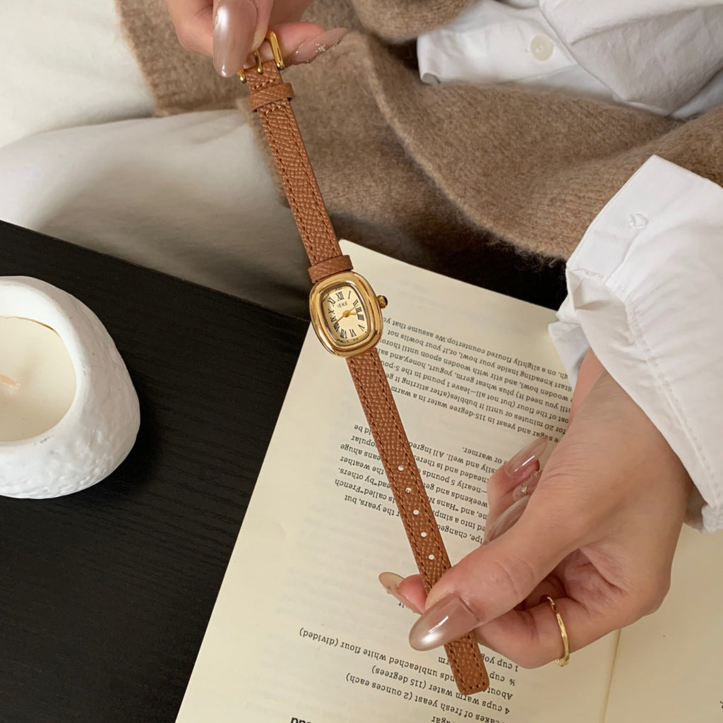 IEKE women's vintage oval Roman numeral watch with brown leather-style strap and gold-tone case in a lifestyle setting
