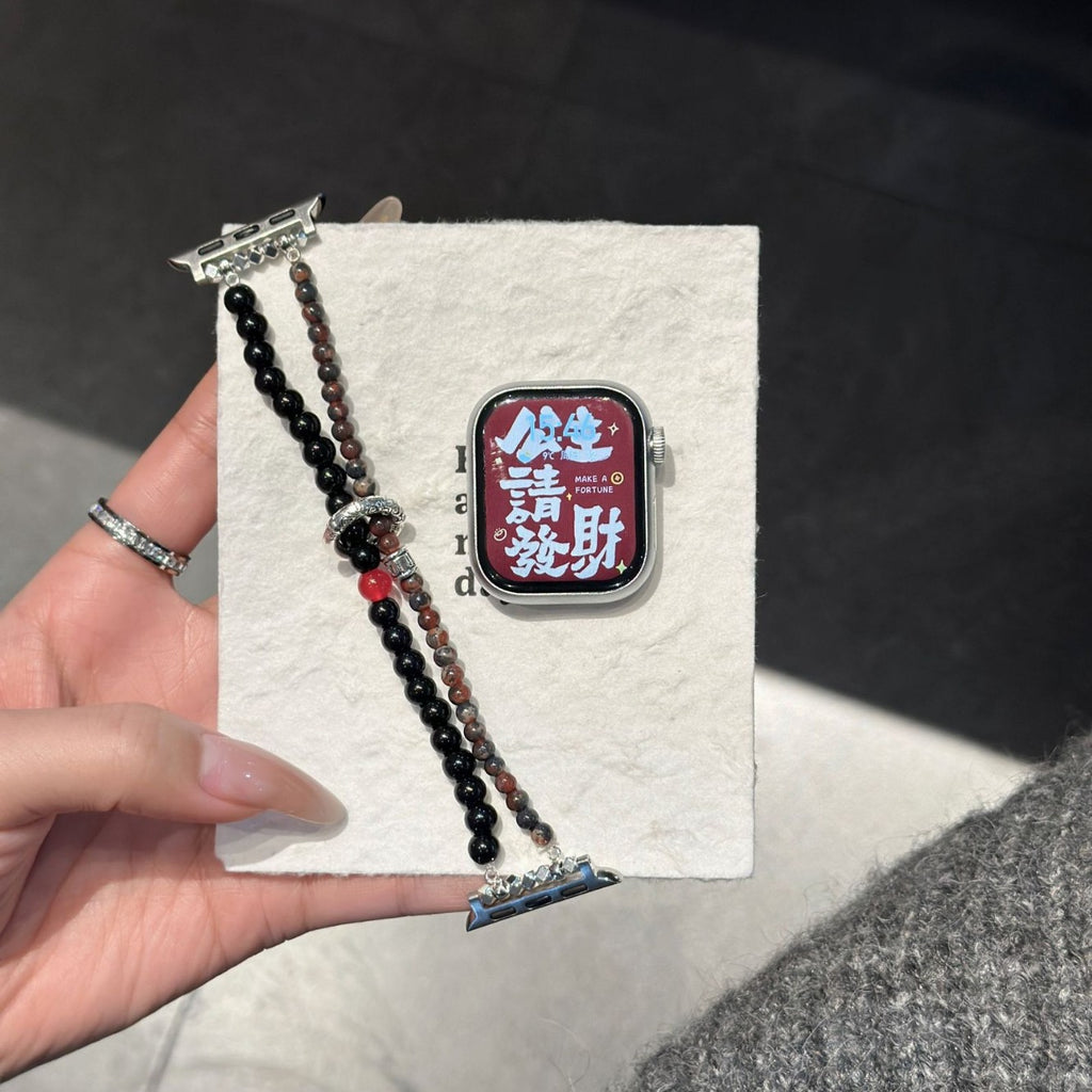 Black brown and red double-strand Apple Watch band displayed on textured card