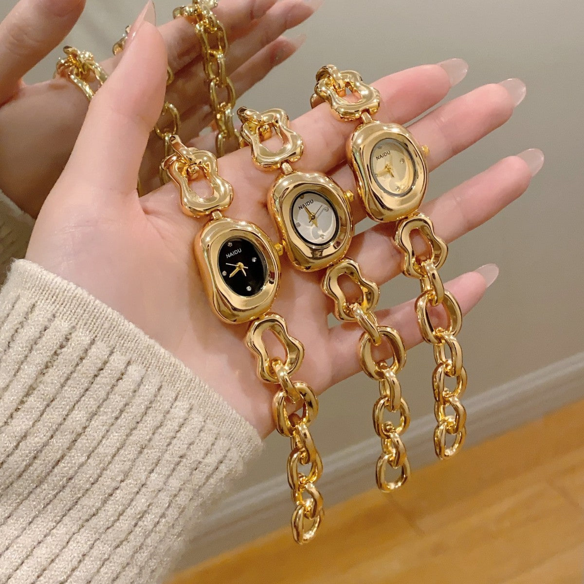NAIDU sculpted-link jewelry watch collection in gold tone with black white and champagne dials
