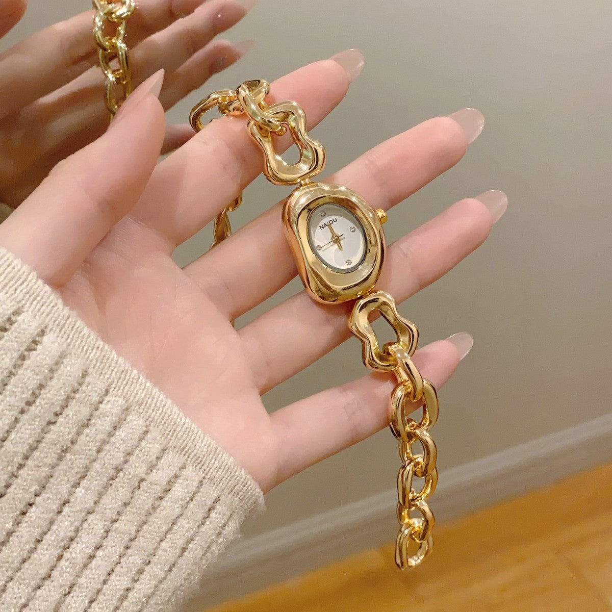 NAIDU sculpted-link jewelry watch in gold tone with white dial hand view