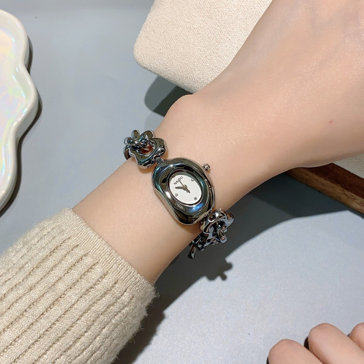 NAIDU sculpted-link jewelry watch in gunmetal tone with white dial worn on wrist