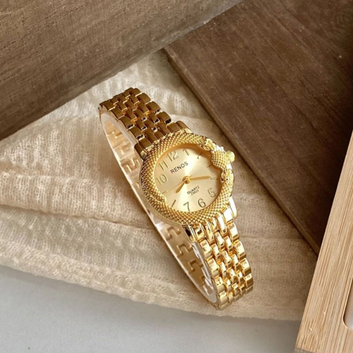 RENOS textured bezel bracelet watch in gold tone with champagne dial
