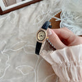 Petite oval women's watch with black strap, champagne dial and gold-tone crystal-style bezel