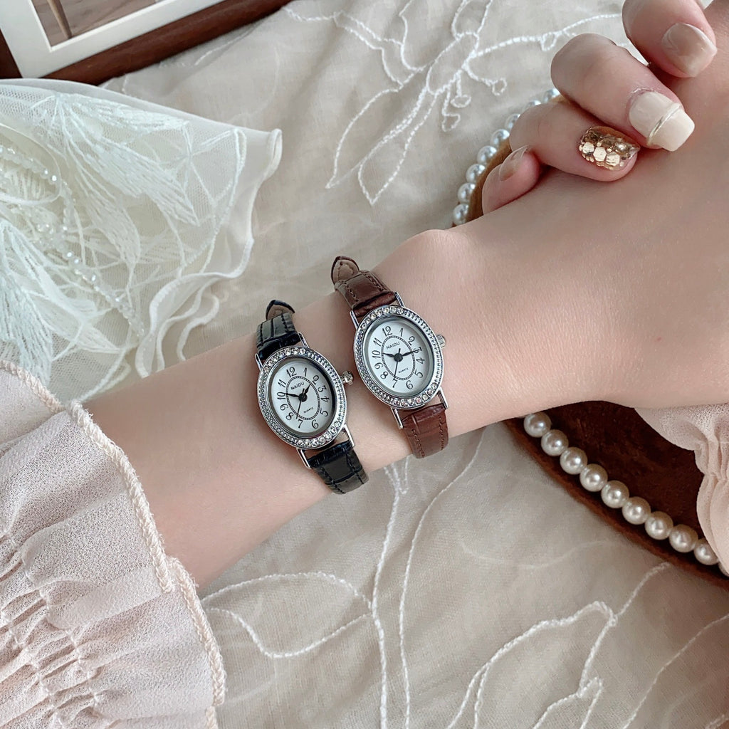 Silver-tone petite oval watches with black and brown straps styled on wrist