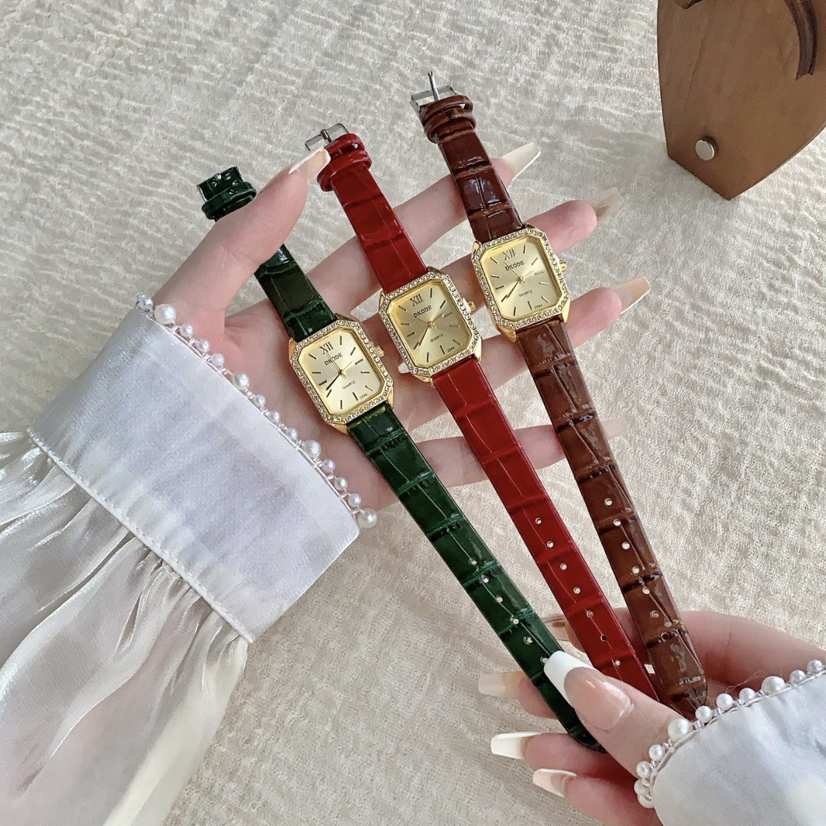 Vintage petite women's watch with crystal-style bezel shown in green, red and brown leather-style straps