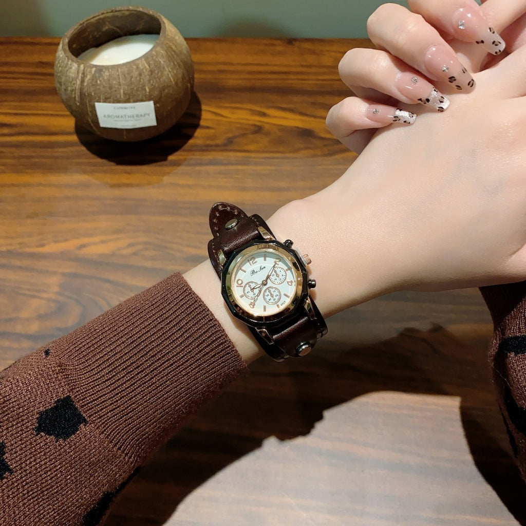 Vintage rivet leather-style women's watch with brown strap and cream dial worn on wrist