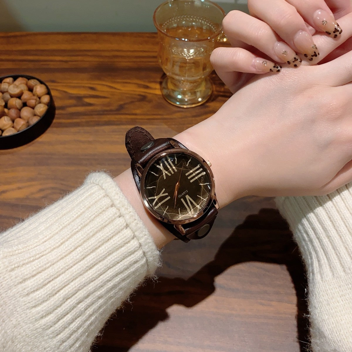 Vintage Roman numeral rivet women's watch with brown leather-style strap and black dial worn on wrist